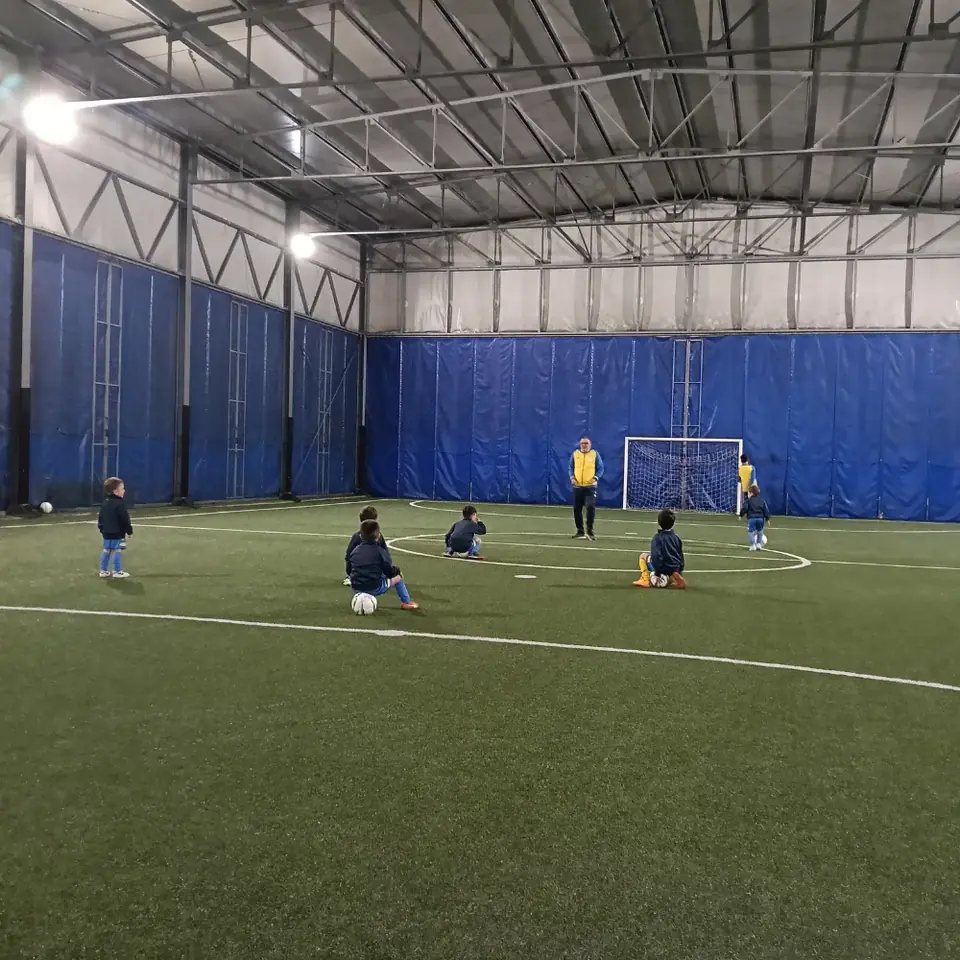 Bambini della scuola calcio durante un allenamento su un campo coperto
